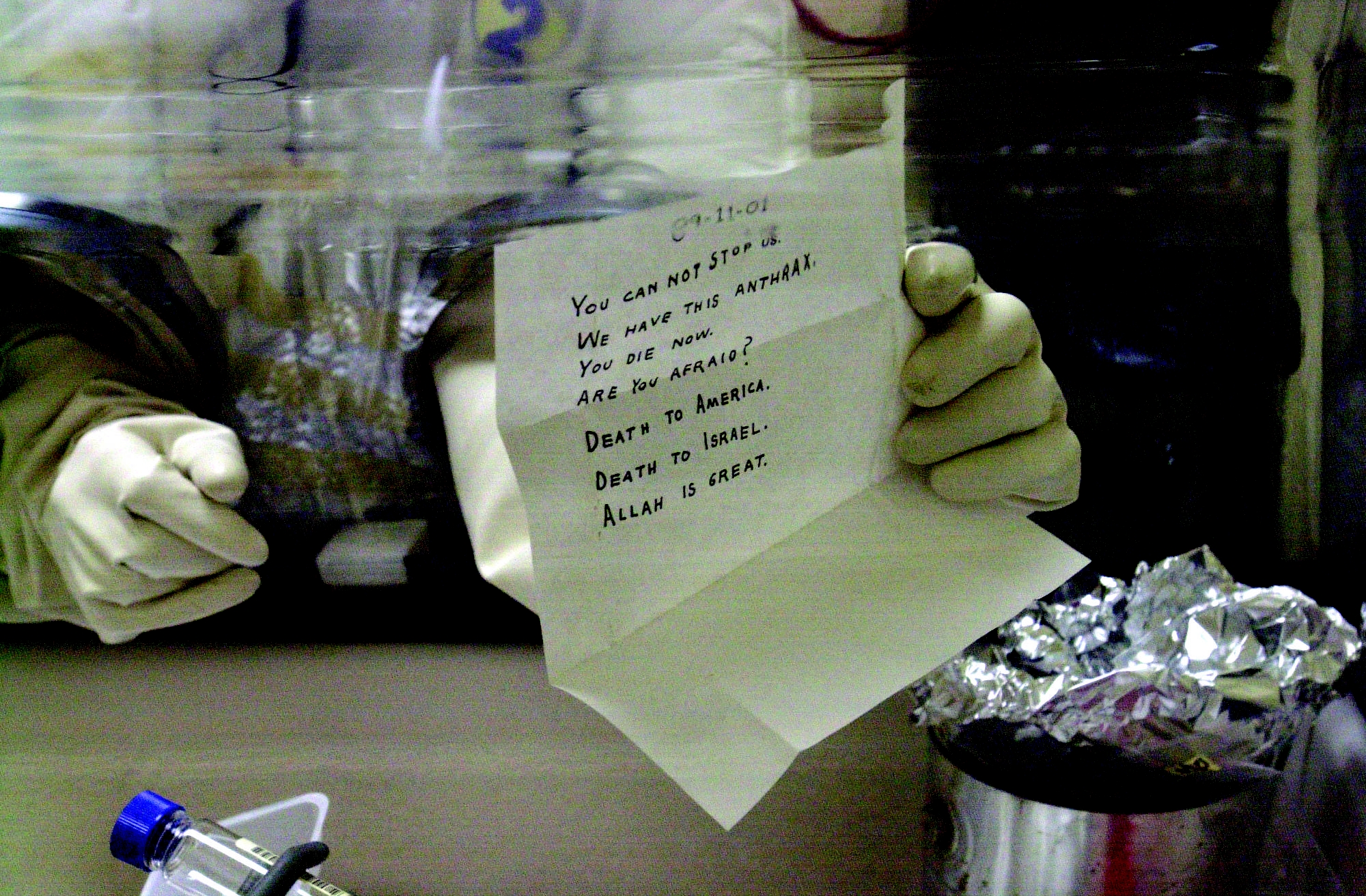 A gloved laboratory technician holds the opened anthrax-laced letter addressed to Senator Patrick Leahy, its block-capital handwriting visible