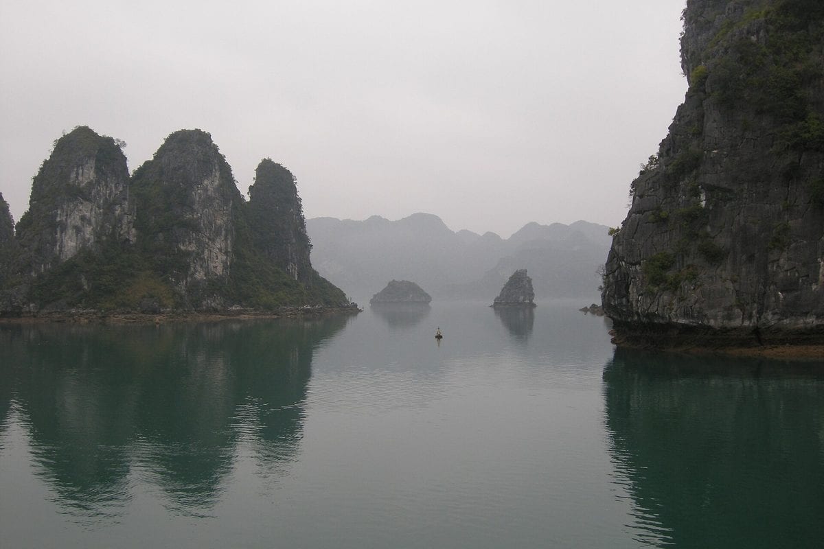 Limestone karst islands rising from the calm water of Ha Long Bay, Vietnam