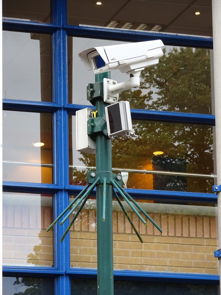 A surveillance camera mounted on a pole outside a building.