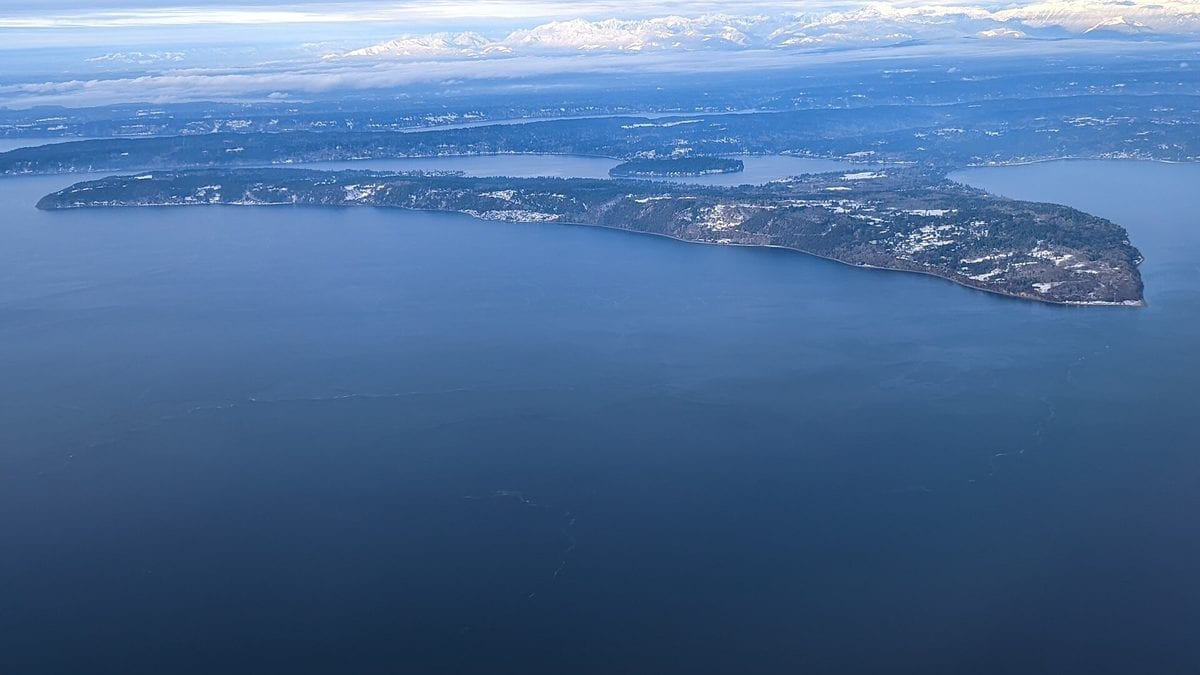 View across the water toward the wooded shoreline of Maury Island in Puget Sound, Washington