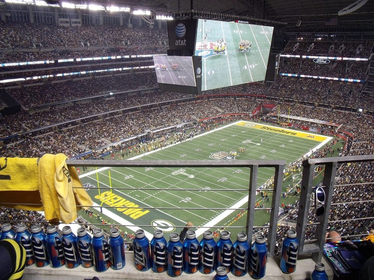 Wide view of a Super Bowl football game in progress inside a large domed stadium, with players lined up on the field and a full crowd in the stands