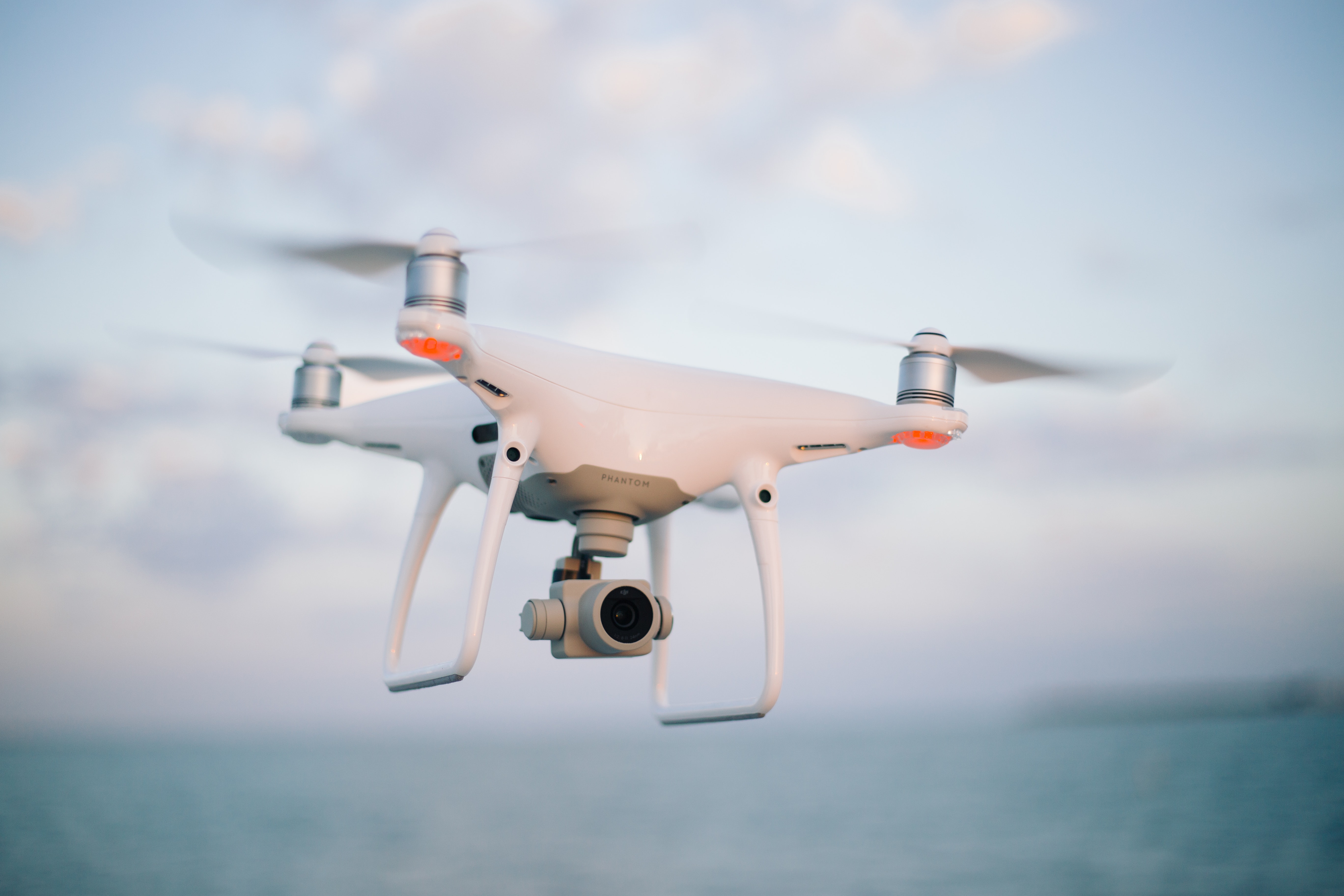 A consumer quadcopter camera drone hovering against the sky