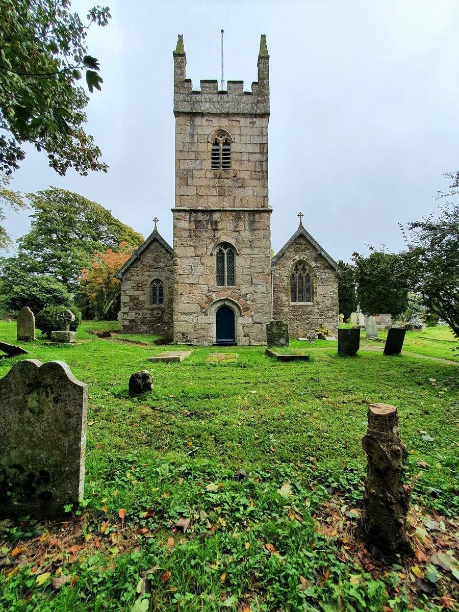 The medieval church of St Mawnan and St Stephen in Mawnan, Cornwall, set among trees, with its stone tower rising above the churchyard.