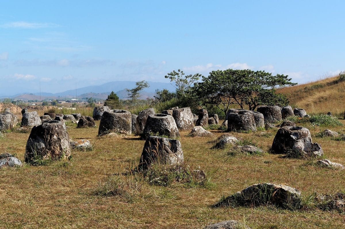Carved stone jars from the Iron Age scattered across a grassy hillside at the Plain of Jars, Xieng Khouang, Laos