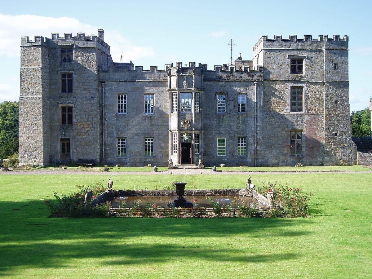 Corby Castle, a red sandstone country house on the edge of Great Corby in Cumbria, England, seen from its grounds