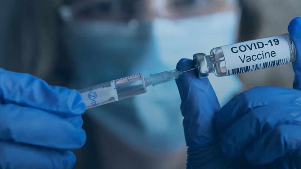 A COVID-19 vaccine vial beside a syringe